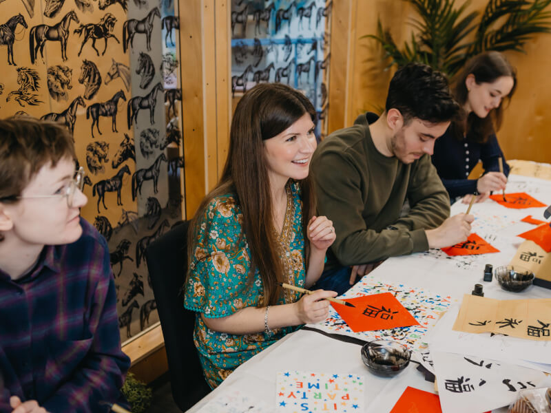 A group of people smiling at a calligraphy class. 